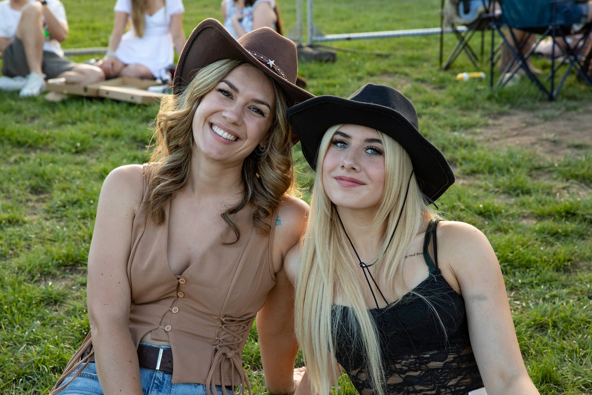 Friends in cowboy hats on the grass at the 2026 festival.